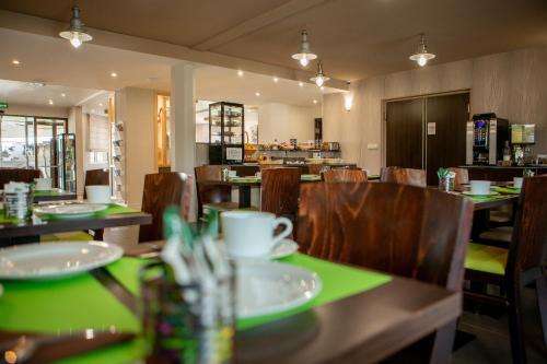 a restaurant with wooden tables and chairs with green plates on them at Hotel Chantereyne in Cherbourg en Cotentin