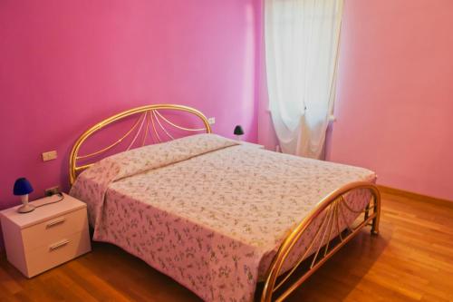 a bedroom with a bed with a pink wall at B&B Casa a colori in Verona