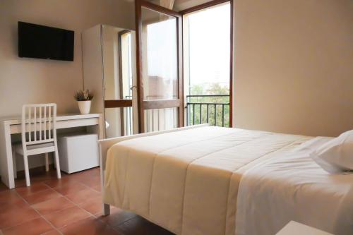 a bedroom with a bed and a desk and a balcony at Gialel Pisa in Pisa