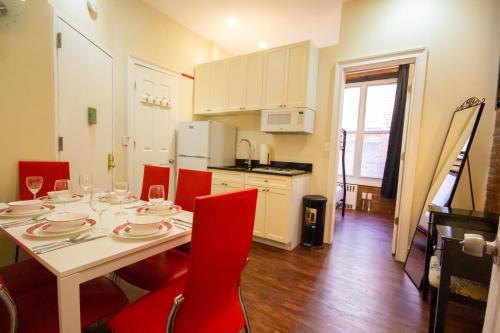 a dining room table with red chairs and a kitchen at STUDIO PLUS - 2 Bedroom Apartment in Midtown in New York