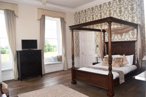 sypialnia z łóżkiem z baldachimem i telewizorem w obiekcie The Clock House w mieście Brewood