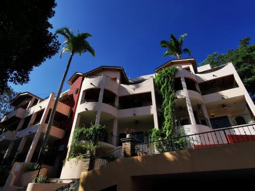 a white building with palm trees in front of it at Villas Vista Suites Sayulita in Sayulita