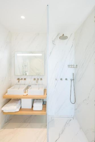 a white bathroom with a sink and a shower at Les Bords De Mer in Marseille