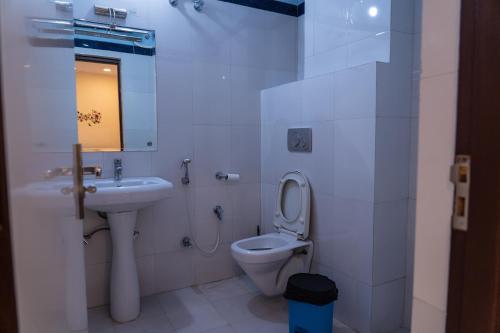 a white bathroom with a toilet and a sink at Swiss House in Jodhpur