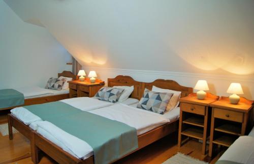 a bedroom with two beds and two tables with lamps at Rácz Fogadó in Kisoroszi