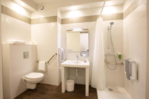 La salle de bains blanche est pourvue de toilettes et d'un lavabo. dans l'établissement Hotel Chantereyne, à Cherbourg en Cotentin