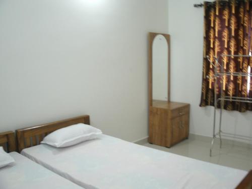 a bedroom with two beds and a dresser and a mirror at Jacaranda Holiday Home in Cochin