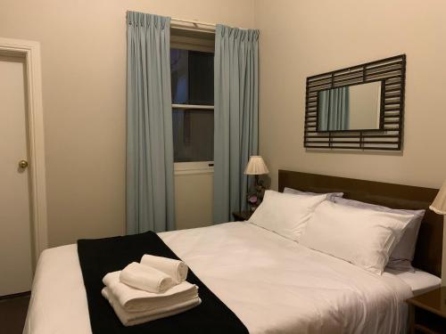 - une chambre avec un lit blanc et des serviettes dans l'établissement Boutique Apartment in The Heart of Adelaide CBD, à Adélaïde