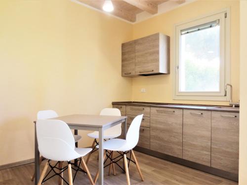 a kitchen with a table and white chairs at Monolocale con giardino a 100m dal mare Punta Ala in Punta Ala