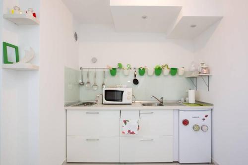 a kitchen with white cabinets and a microwave at A bright hideaway in Dubrovnik