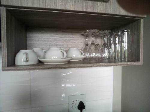 a shelf with dishes and glasses on it at Rosebank Accommodation in Johannesburg