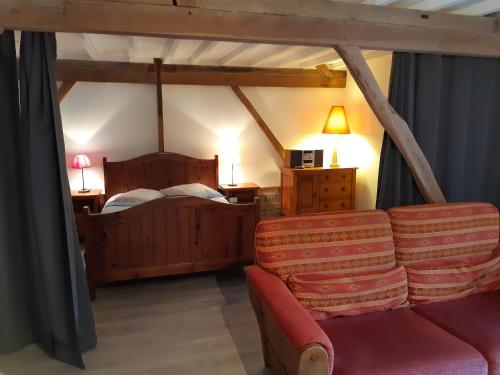 ein Schlafzimmer mit einem Bett und einem Sofa in einem Zimmer in der Unterkunft Logement à la ferme in Hangest-en-Santerre