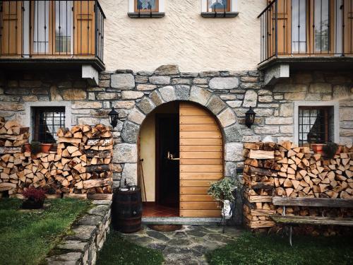 a building with a wooden door and a pile of logs at Casa Brencio in Masera