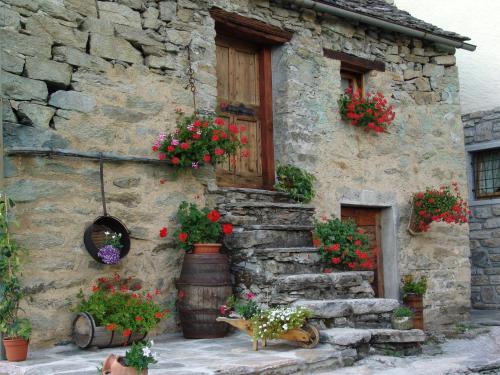 an old stone house with flower pots and a window at Casa Brencio in Masera