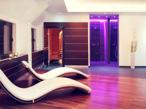 a bathroom with two white chairs on the floor at Mercure Hotel Hamm in Hamm