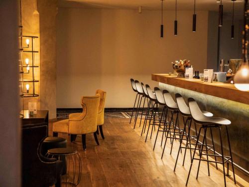 a bar with a row of chairs and a counter at Mercure Hotel Hamm in Hamm