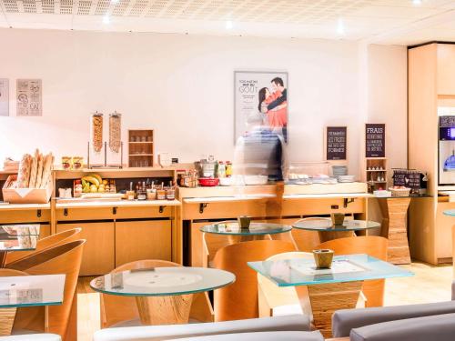 un restaurant avec des tables et des chaises et une cuisine dans l'établissement ibis Quimperle, à Quimperlé