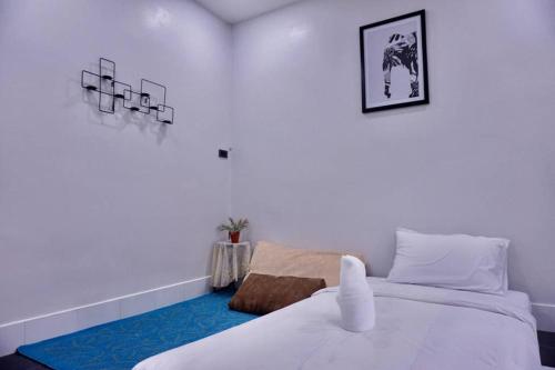 a bedroom with a white bed and a blue carpet at พี่จ๋า เฮ้าส์ P'Ja House in Ban Kohong