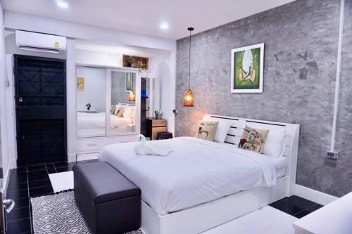 a bedroom with a large white bed and a bathroom at พี่จ๋า เฮ้าส์ P'Ja House in Ban Kohong