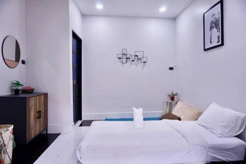a white bedroom with a large bed and a mirror at พี่จ๋า เฮ้าส์ P'Ja House in Ban Kohong