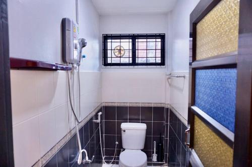 a bathroom with a toilet and a window at พี่จ๋า เฮ้าส์ P'Ja House in Ban Kohong