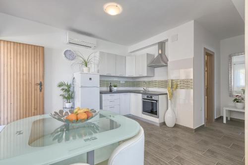 a white kitchen with a bowl of fruit on a table at Apartments Gilly 2 in Premantura
