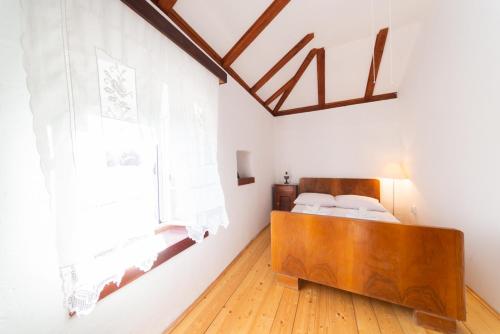 1 dormitorio con cama de madera y ventana en Holiday Home Burba en Komiža