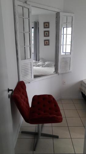 una silla roja en una habitación con espejo en Apartamento quadra mar, en Balneário Camboriú