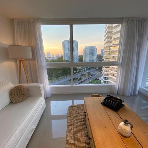 a living room with a white couch and a large window at Torre One II Punta Del Este in Punta del Este