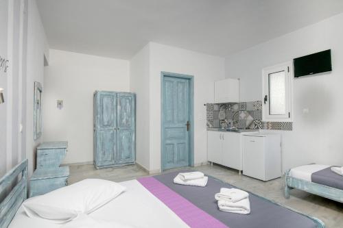 a white room with a bed and a kitchen at Studios Tasos in Chrysi Ammoudia
