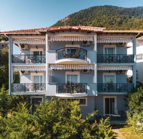 an apartment building with balconies and trees at Studios Tasos in Chrysi Ammoudia