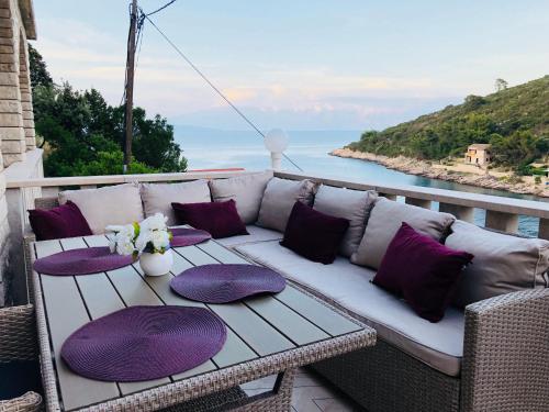 a white couch sitting on a porch with purple pillows at HVAR BEACH VILLA in Jelsa