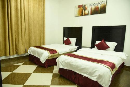 twee bedden in een kamer met een geruite vloer bij شقق جنان المفروشة Jenaan Apartments in Najran