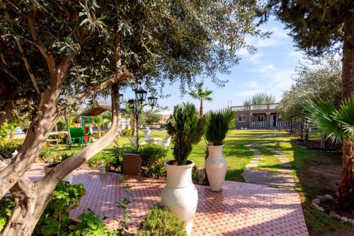 two white vases with plants in them on a sidewalk at Villa Ayche in Marrakech