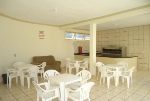 Habitación con mesas y sillas blancas y cocina. en Residencial Varanda dos Buritis, en Caldas Novas
