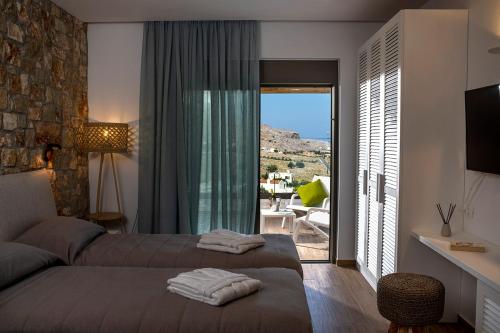 a bedroom with a bed and a balcony with a view at Villa Alkyoni Lindos in Líndos