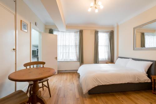 een slaapkamer met een bed en een houten tafel bij Evelyn Court in Londen