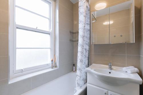 een badkamer met een wastafel en een raam bij Evelyn Court in Londen