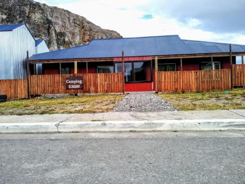 ein rotes Gebäude mit einem Zaun vor einem Berg in der Unterkunft Hostel El Paredon in El Chalten