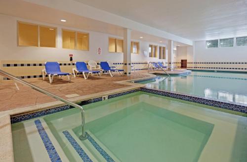 a swimming pool with blue chairs in a building at Candlewood Suites-West Springfield by IHG in West Springfield