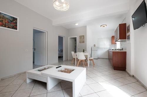 a white living room with a table and a kitchen at Stavroula Studios in Paleokastritsa