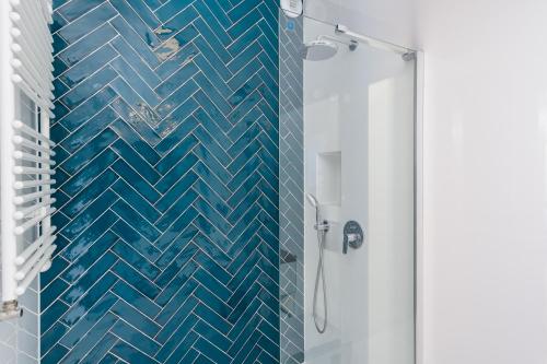 e bagno con doccia e parete piastrellata blu. di Apartament Małe Garbary a Poznań