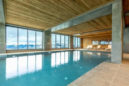 une piscine intérieure avec un plafond en bois et des fenêtres dans l'établissement Les ARCS 1600 - SKI AUX PIEDS - MAGNIFIQUE DUPLEX 12 PERSONNES, à Bourg-Saint-Maurice