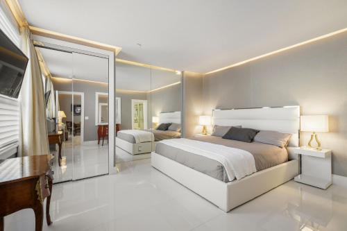 um quarto com uma grande cama branca e um espelho em ORCHID SUITES - Historic Palm Beach Hotel Condominium em Palm Beach