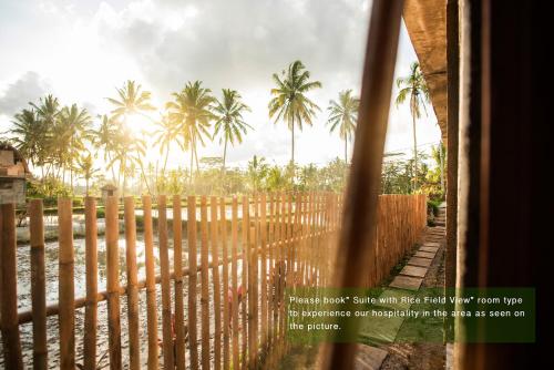 a view from a window of a fence with palm trees at Ayu Duwur Beji in Ubud