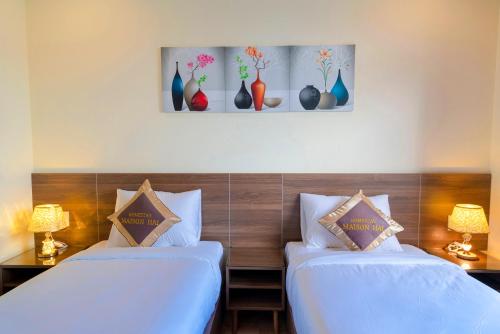two beds in a room with vases on the wall at Maison Hai Homestay Hoi An in Hoi An