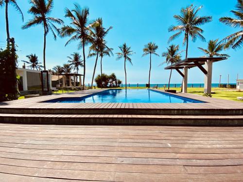 a swimming pool with palm trees on the beach at The Lighthouse Negombo in Negombo