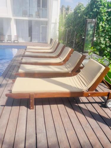 a row of chaise lounges on a deck near a pool at The Lighthouse Negombo in Negombo