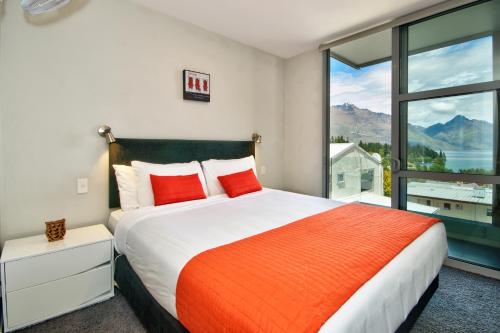 a bedroom with a large bed and a large window at Luxury on the Lake in Queenstown