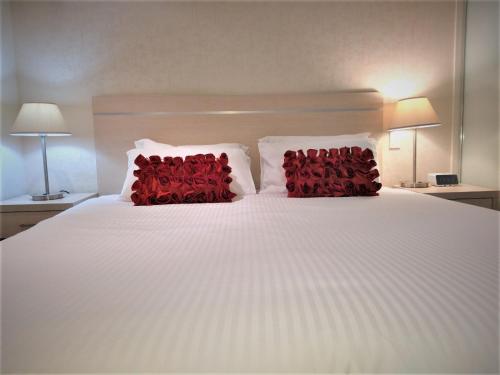 a white bed with two red pillows on it at Hi 5 star luxury Adelaide City Apartment in Adelaide